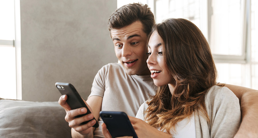 Young couple on sofa using smartphones